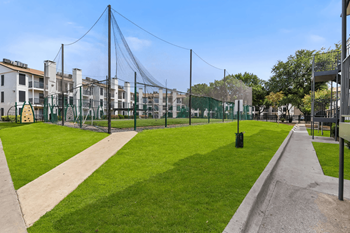 a park with a green lawn and a suspension bridge